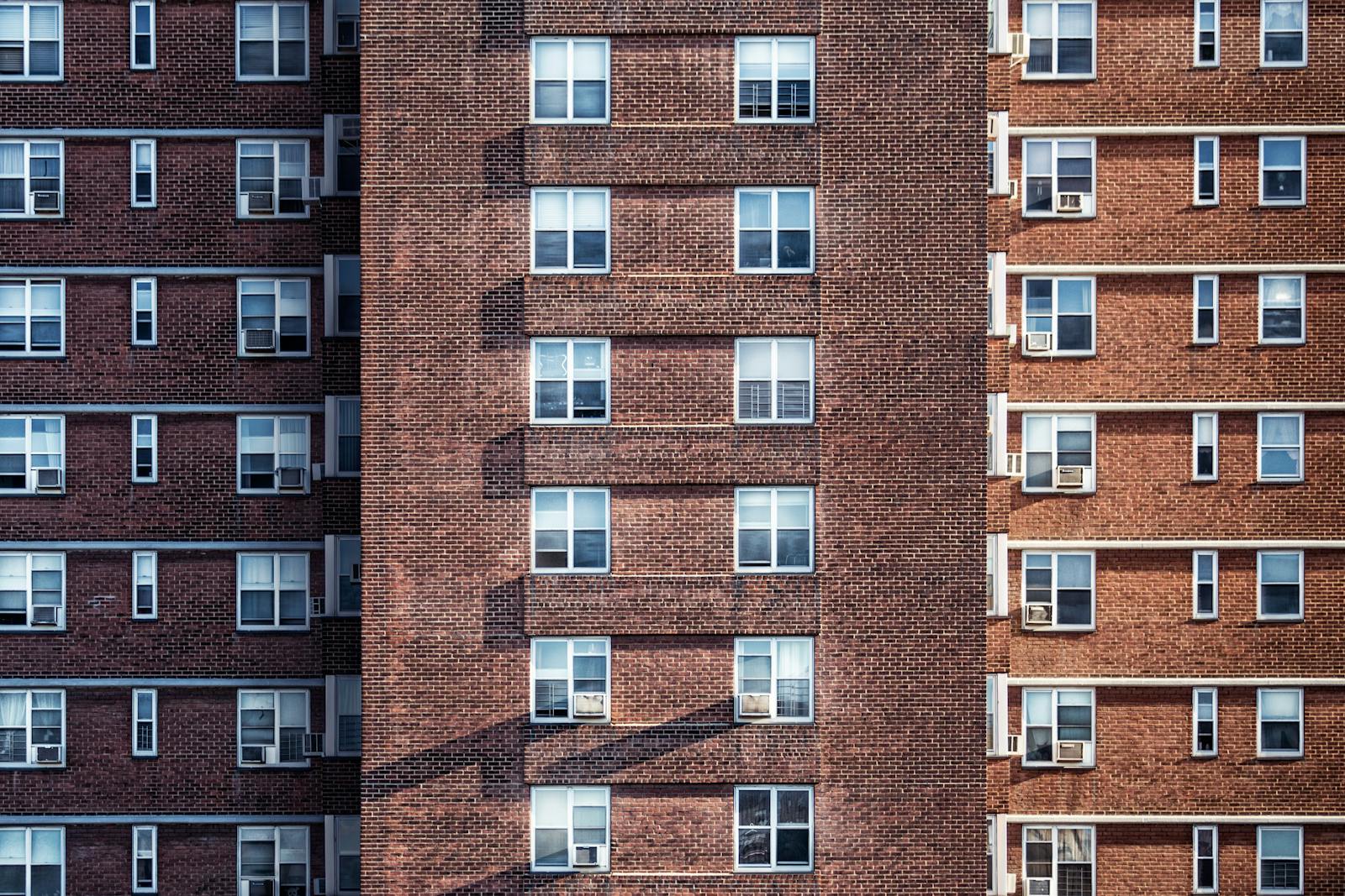 Close-up view of a high-rise brick building facade with multiple windows and air conditioning units, condo, home